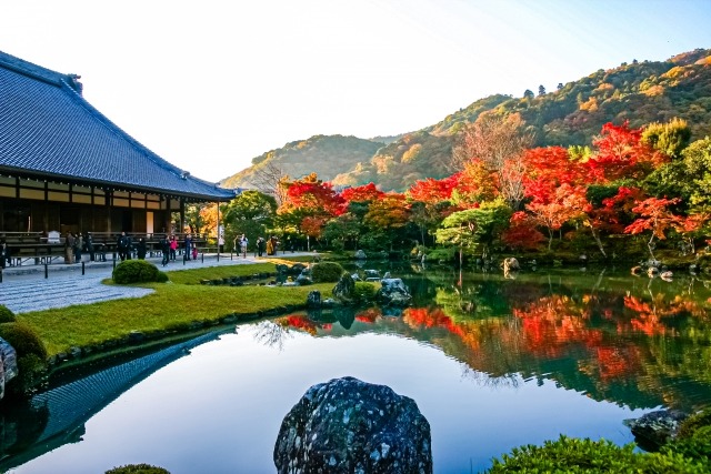 Tenryu-ji temple zen garden with pond reflecting autumn foliage and mountains Arashiyama